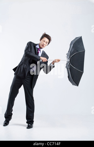 Ein Mann schlug durch den starken Wind mit einem Regenschirm in-und auswendig Stockfoto