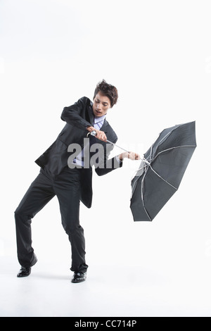 Ein Mann schlug durch den starken Wind mit einem Regenschirm in-und auswendig Stockfoto