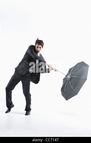 Ein Mann schlug durch den starken Wind mit einem Regenschirm in-und auswendig Stockfoto