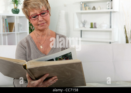 Großmutter blättert in Familienalbum in lounge Stockfoto