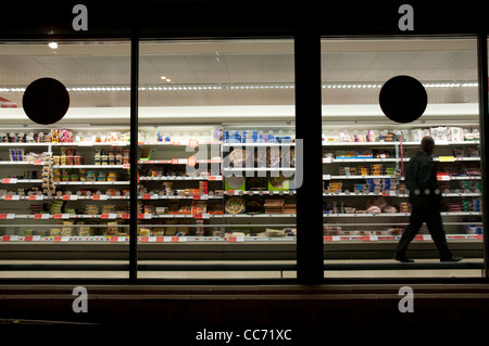 Schwarze männliche Einkaufen in einem kleinen Supermarkt nach Einbruch der Dunkelheit, fotografiert von außerhalb Stockfoto