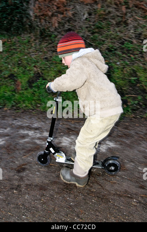 Ein kleiner Junge auf einem Roller Stockfoto