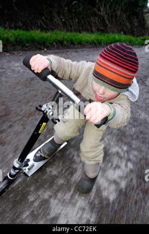 Ein kleiner Junge auf einem Roller Stockfoto