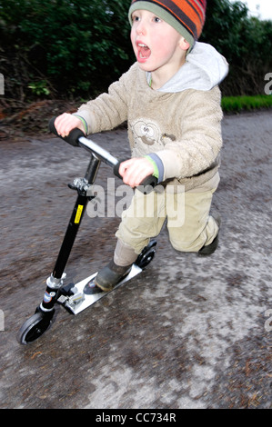 Ein kleiner Junge auf einem Roller Stockfoto