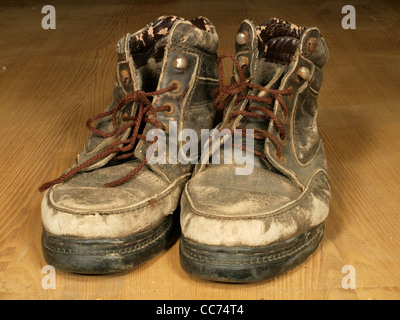 Das alte abgenutzt Stiefel mit braunen Spitzen auf einen Boden aus Holz. Stockfoto