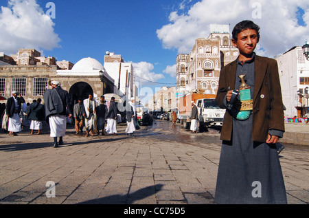 Jemen, Sanaa, niedrigen Winkel Ansicht eines traditionell gekleideten Jungen stehend mit Passanten im Hintergrund Stockfoto