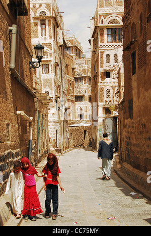 Jemen, Sanaa, drei kleine Kinder zu Fuß entlang der schmalen Gasse inmitten von alten Gebäuden Stockfoto