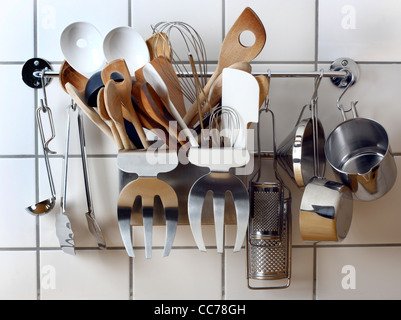 Diverse Küchenutensilien, Küchengeräte, hängen an einem Küche Wand Rack. Stockfoto
