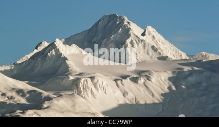 Die Berge unter einer Decke von Schnee mit blauem Himmel hinter. Alaska. Stockfoto