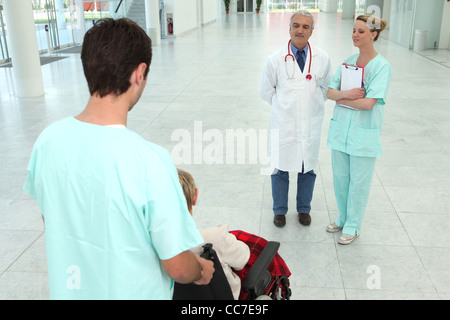 Krankenhaus-Mitarbeiter kümmert sich um ältere Patienten im Rollstuhl Stockfoto