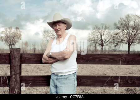 Senior Woman im Cowboy-Hut stehen in der Nähe von Holzzaun Stockfoto