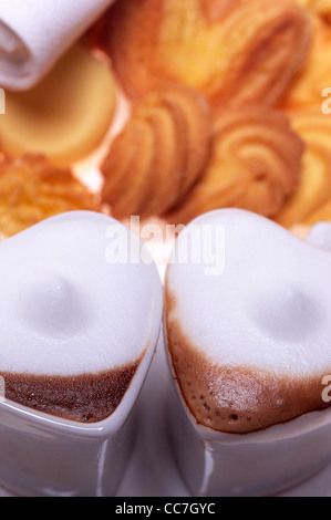 herzförmige Espresso Kaffee Cappuccino-Tassen mit Auswahl an Gebäck auf Hintergrund Valentine Tag behandeln Stockfoto