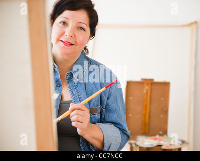 Hispanic Frau malen auf Leinwand Stockfoto