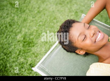 Lächelnde schwarze Frau Verlegung auf Liegestuhl Stockfoto