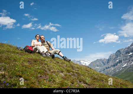 Paar sitzt am Berghang, Berner Oberland, Schweiz Stockfoto