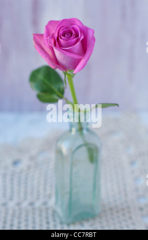 Rosa Rose in einer Vintage Flasche auf einer Matte häkeln Stockfoto