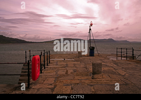 Tagesanbruch über den Wellenbrecher am Eingang nach Lyme Regis Hafen, Dorset, England, UK Stockfoto