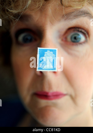 Applying Frau nahe Gesicht mit einem britischen zweiten 2. Klasse Briefmarke klebte an Nase Modell Stockfoto