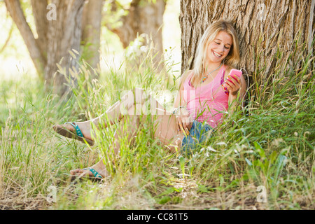 Kaukasische Frau sitzt in Gras- und Text-messaging Stockfoto