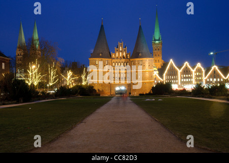 Beleuchtete Holstentor oder Holstentor am Abend mit Weihnachtsschmuck, Hanseatic Stadt von Lübeck, Deutschland Stockfoto