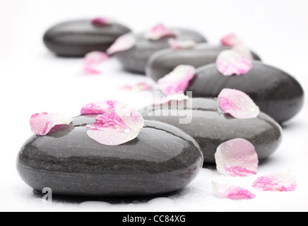 Spa-Steinen mit Rosenblättern auf weißem Hintergrund. Stockfoto