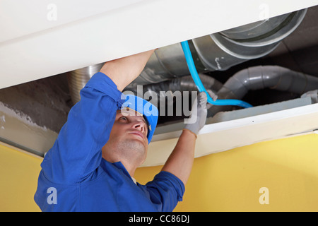 Arbeiter mit blauen Rohr im Rahmen der Luftkanäle Stockfoto