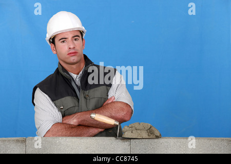 Maurer mit einer Blockwand Stockfoto