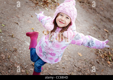 glücklich lächelnde Mädchen in einem wolligen rosa Hut und Winterjacke Stockfoto