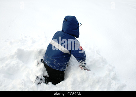 ein kleiner Junge in blau spielt im Schnee Stockfoto