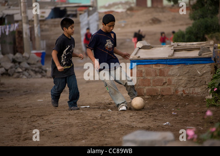 Kinder spielen Fußball in den sandigen Straßen ein Slum in Lima, Peru, Südamerika. Stockfoto