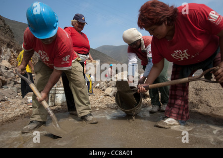 Ein Bauarbeiter baut eine neue Mauer an einem Hang in Lima, Peru, Südamerika. Stockfoto