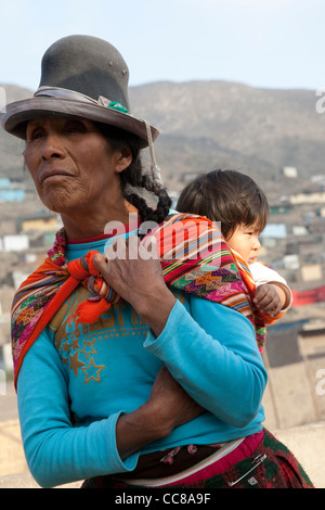 Eine Frau trägt ein Baby auf dem Rücken in einem Armenviertel von Lima, Peru, Südamerika. Stockfoto