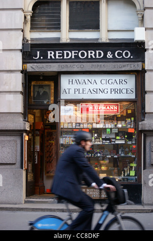 J. Redford & Co. Zigarre kaufen, 33 Royal Exchange, City of London, England mit einem Mann auf einem Boris-Bike vor Stockfoto