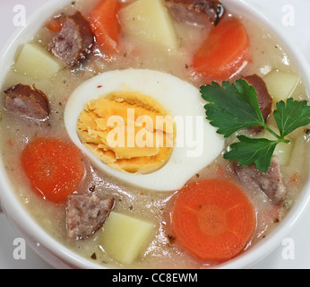 Traditionelle polnische weiße Borschtsch mit Eiern und Wurst in weißem Geschirr für Ostern Stockfoto