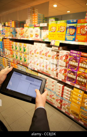 Handheld Tablet in einem Supermarkt Regal für die Übernahme von Getreide durch die Mann in Anzug, Armen hielt nur Stockfoto