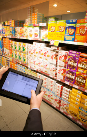 Handheld Tablet in einem Supermarkt Regal für die Übernahme von Getreide durch die Mann in Anzug, Armen hielt nur Stockfoto