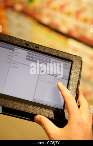 Handheld Tablet in einem Supermarkt Regal für die Übernahme von Getreide durch die Mann in Anzug, Armen hielt nur Stockfoto