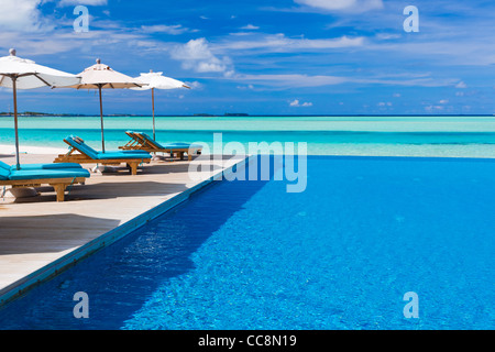 Liegestühle und Infinity-Pool über erstaunliche tropische Lagune Stockfoto