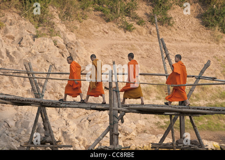 Junge buddhistische Mönche zu Fuß über eine Bambusbrücke in Luang Prabang, Laos Stockfoto