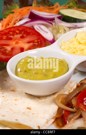 Chicken Fajitas mit Gemüse, serviert mit Guacamole und Käse Stockfoto