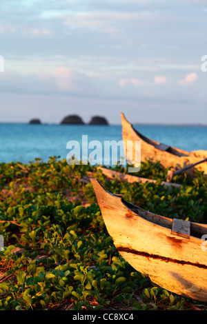 Zwei gestrandet Outrigger Kanus oder Pirogen, madagassische Segelschiff, mit drei kleinen Inseln im Hintergrund bei Sonnenuntergang