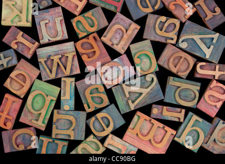 Buchstaben des Alphabets in Vintage Holz Buchdruck Blöcke nach dem Zufallsprinzip auf schwarzem Hintergrund platziert Stockfoto