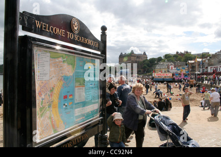 Scarborough's South Bay Seafront, Mai 2006. Touristeninformationsschild mit überfülltem Strand, dem berühmten Grand Hotel im Hintergrund. Stockfoto
