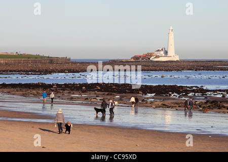 Menschen, die Ausübung der Hunde am Strand von Whitley Bay Nordostengland, UK mit Str. Marys Insel im Hintergrund Stockfoto