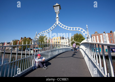 Ein Obdachloser sitzt auf Ha Penny Brücke über den Liffey-Fluss in Richtung untere Ormond Quay Central Dublin Irland. Stockfoto