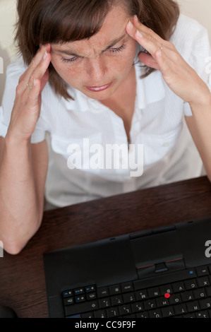Business-Frau mit Kopfschmerzen in Arbeit Stockfoto