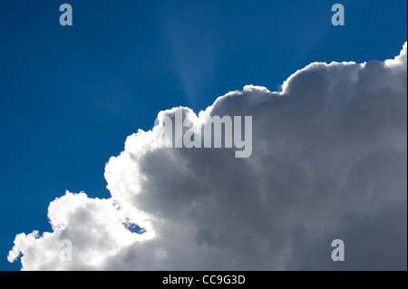Strahlen der Sonne lugt hinter eine Wolke, mit blauem Himmel & Silberstreifen am Horizont Stockfoto