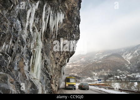 Fahrzeugen, auf einem gefrorenen Straße mit Eiszapfen wachsen im Winter auf einer überhängenden Felswand entlang dem Tal des Flusses Vrbas Bosnien und Stockfoto