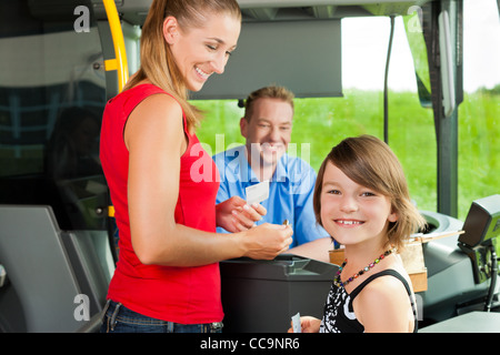 Mutter und Kind einsteigen in einen Bus und ein Ticket kaufen Stockfoto