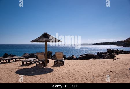 leeren Sie Sonnenliegen in Playa Blanca mit Blick auf Faro de Pechiguera Stockfoto
